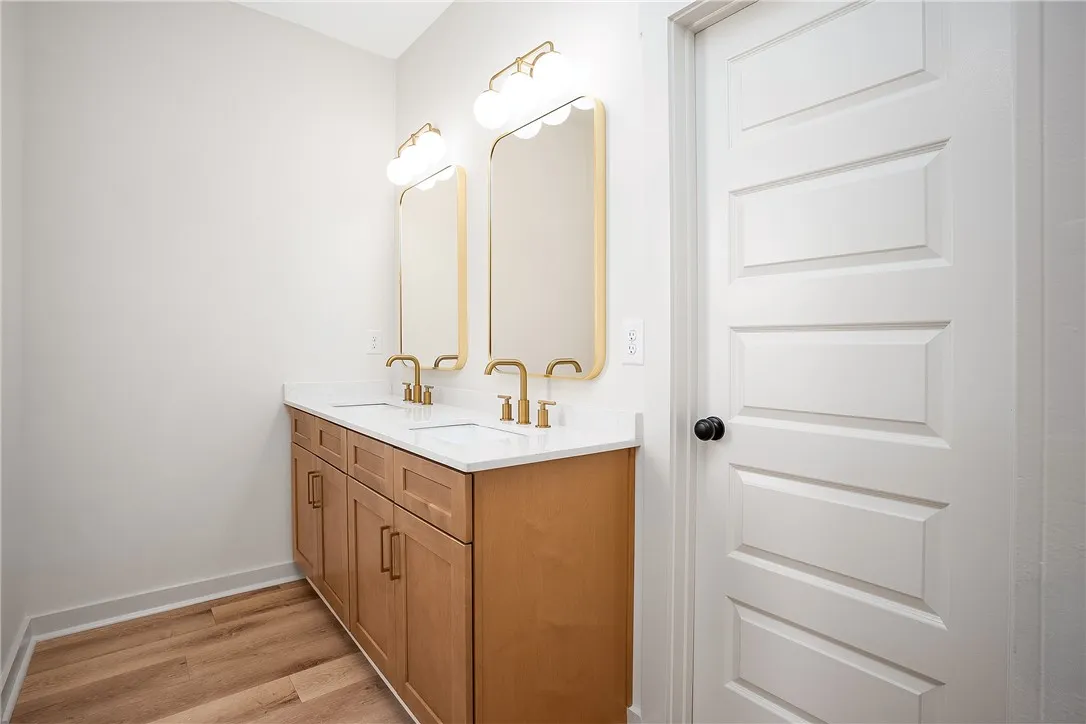 Gleaming stone counters and warm wood flooring define this elegant dual-sink vanity space.