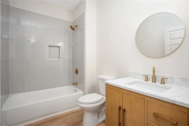 A modern vanity with stone counters complements the beautifully tiled shower and tub combination.