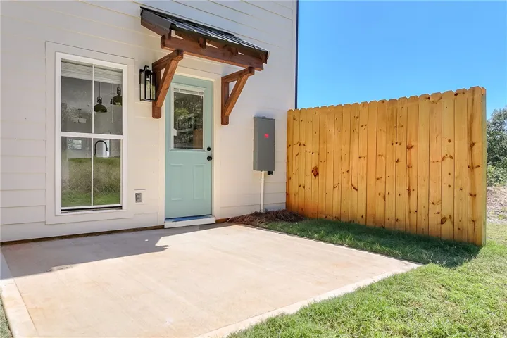 A neat concrete patio opens directly to the grassy backyard bordered by a wooden privacy fence.
