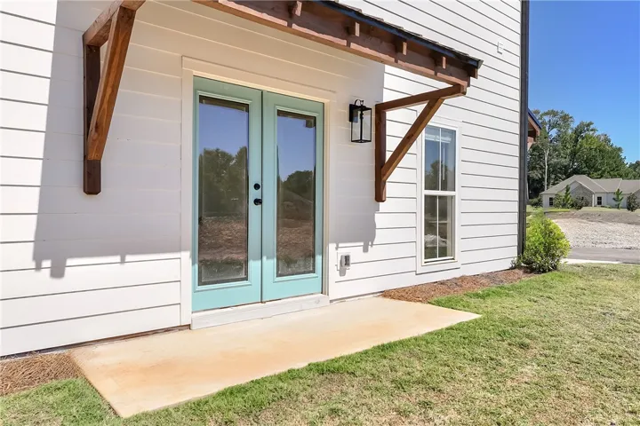 Double glass doors sit beneath a wooden awning on the concrete patio.