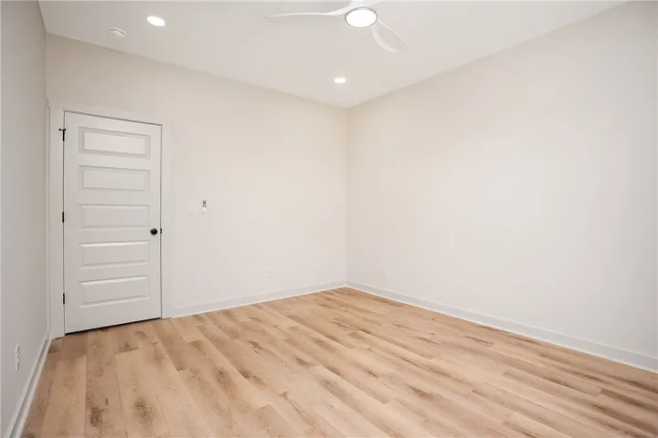 Warm wood-style flooring anchors this versatile bedroom with smooth neutral walls.