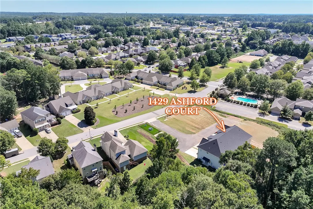 An aerial perspective showcases the surrounding neighborhood and lush green canopies of mature trees.