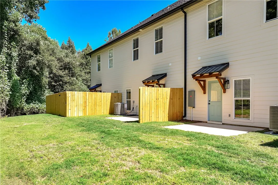 Green grass stretches alongside a neat privacy fence framing the rear entry.