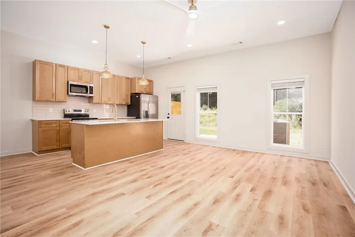 An open floor plan integrates a modern kitchen with a versatile, sun-drenched living area.