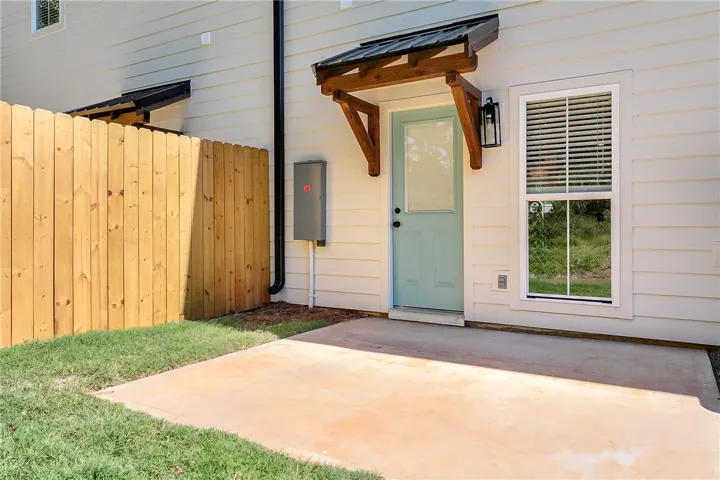 An inviting concrete patio sits adjacent to a private, wood-fenced backyard.