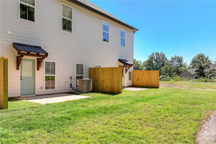 Concrete patios connect the back of this home directly to a grassy yard.