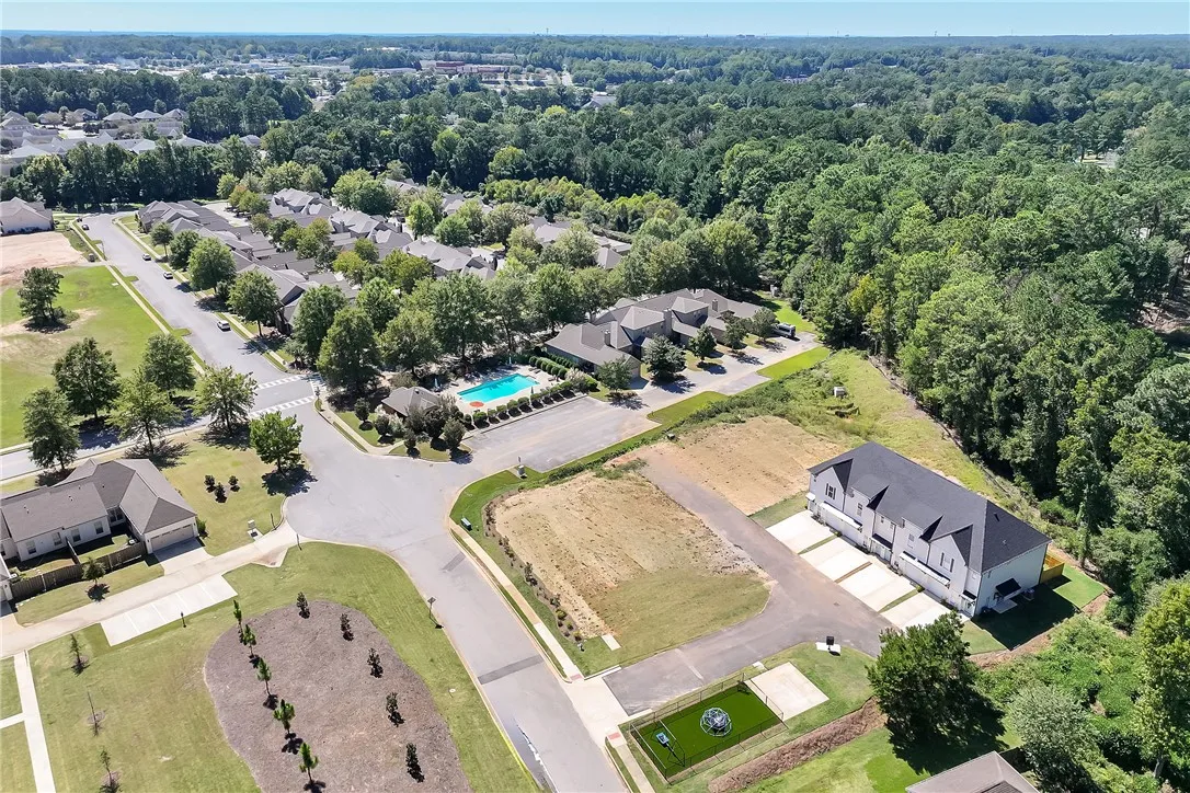 An aerial perspective captures the peaceful residential neighborhood surrounded by mature woodlands.