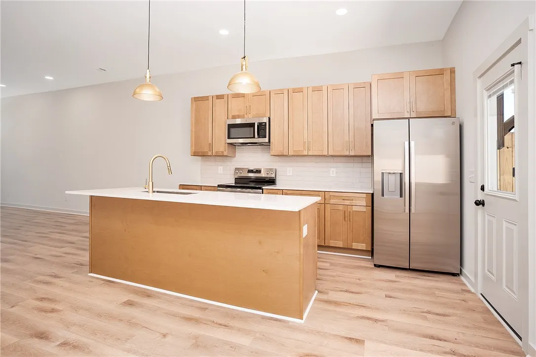 Warm wood cabinetry and an expansive central island anchor this modern culinary workspace.