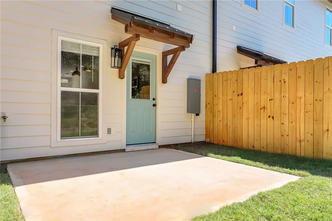 A concrete patio borders the green lawn alongside a wooden privacy fence.