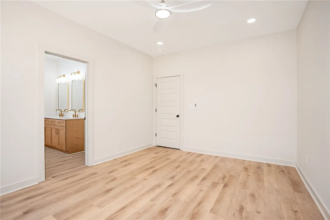 Smooth wood-plank flooring runs from a spacious bedroom directly into an attached private bath.