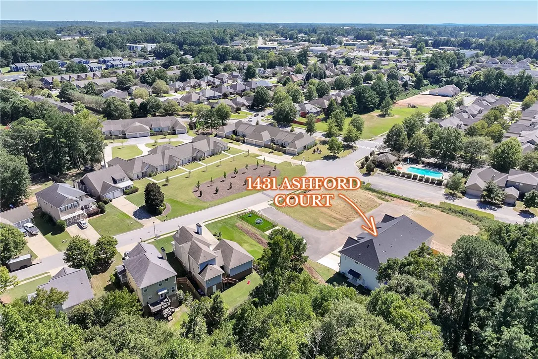 An aerial perspective captures this neighborhood of single-family homes nestled among mature green trees.