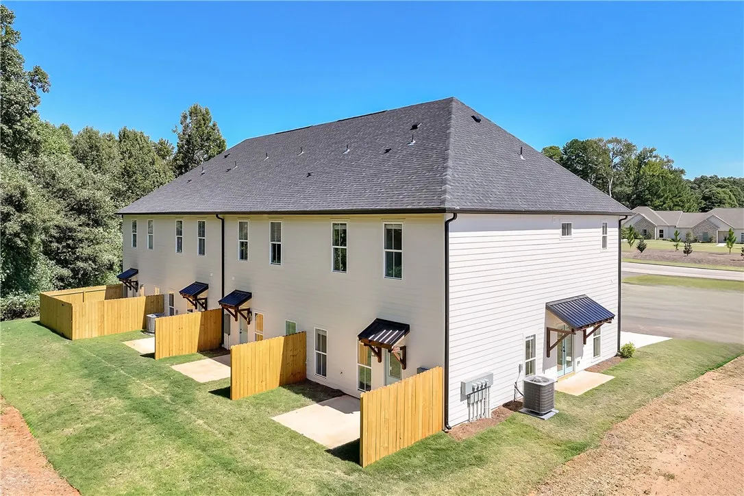 Fenced patios open to a grassy lawn beneath a classic shingle roof.
