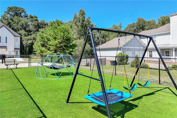 Fenced outdoor recreation area featuring premium artificial turf and modern play structures.
