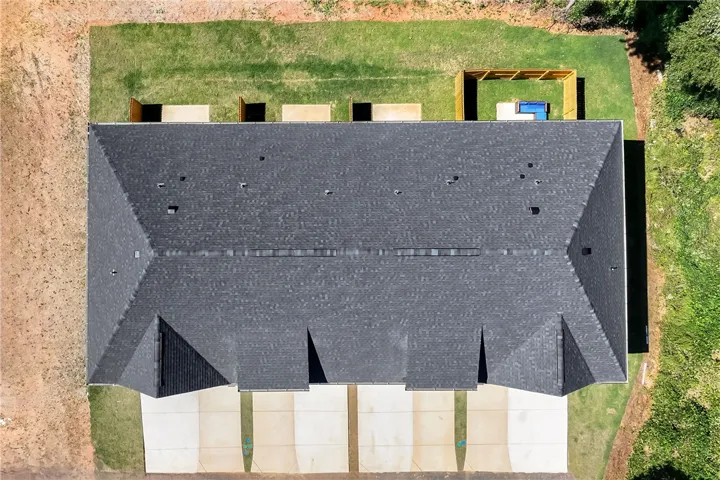 An aerial perspective showcases the structured layout of the shingled roof and surrounding green spaces.