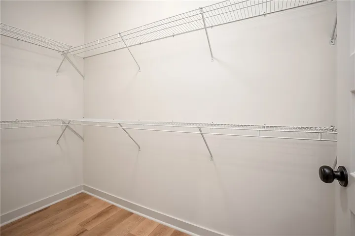 Ample wire shelving lines this functional walk-in closet space featuring durable wood-look flooring.