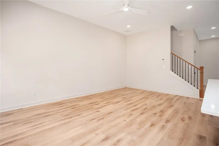 Smooth wood floors and recessed lighting anchor this open living space adjacent to the staircase.