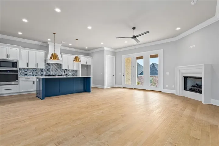 The living space is filled with natural light. A corner fireplace adjacent to a full light door system anchor the room.