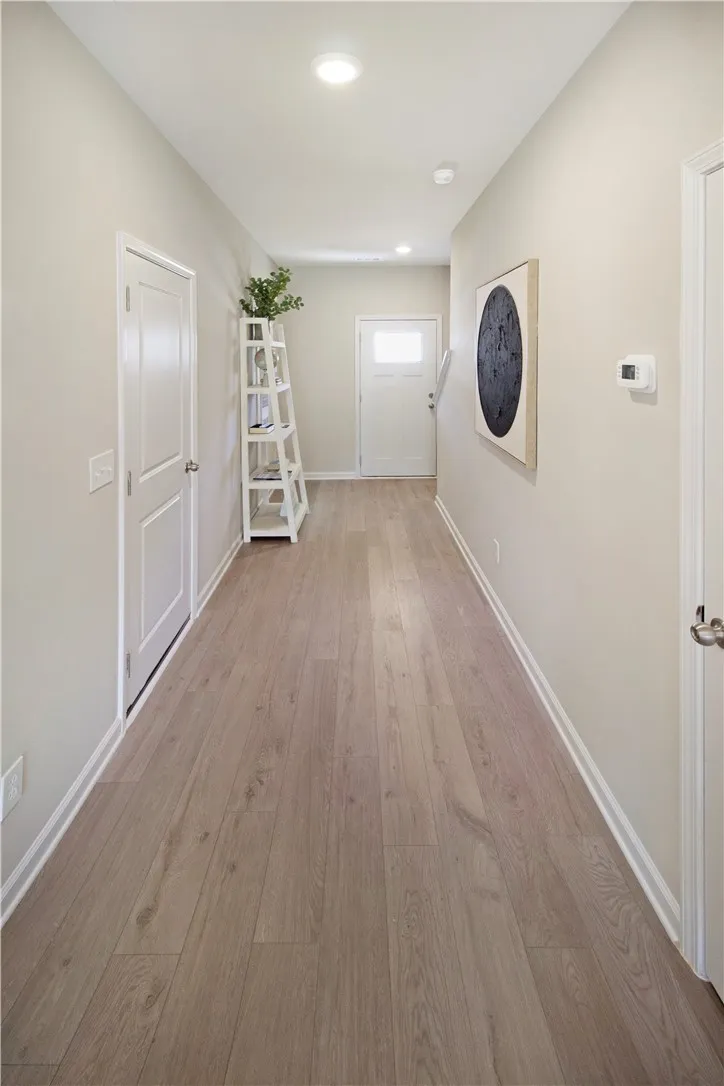A long, inviting hallway featuring durable flooring and modern recessed lighting.