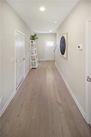 A long, inviting hallway featuring durable flooring and modern recessed lighting.