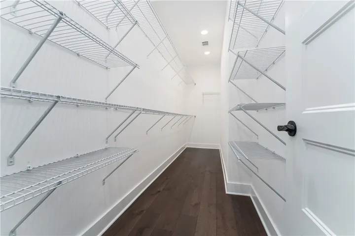 This spacious walk-in closet offers ample storage with convenient shelving and rich hardwood flooring.