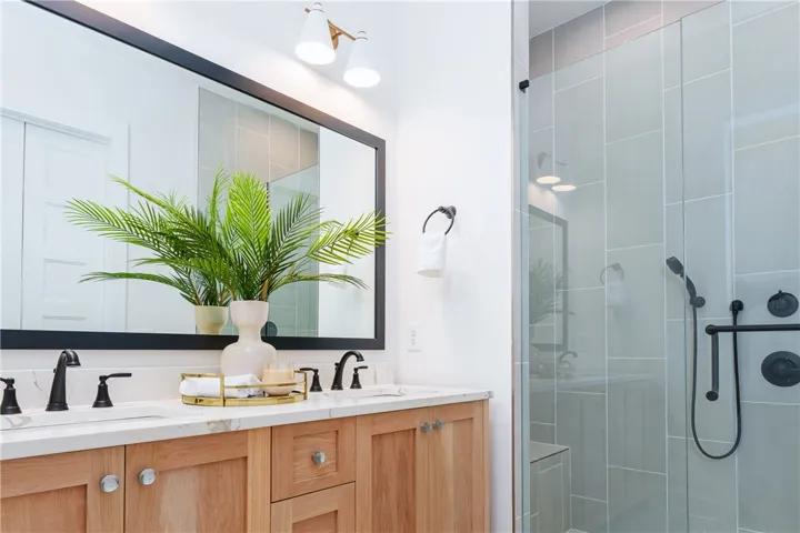 This serene bathroom features a spacious double vanity and a sleek, modern glass-enclosed shower.