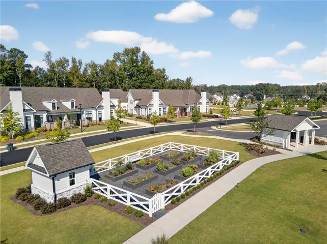 This aerial view showcases a vibrant community garden amidst well-maintained residences and paved pathways.