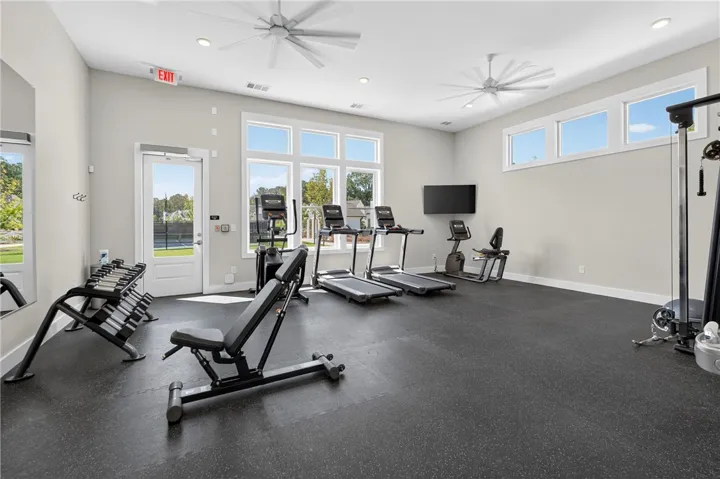 This fitness center offers ample space for various workouts, featuring resilient flooring and bright natural light.