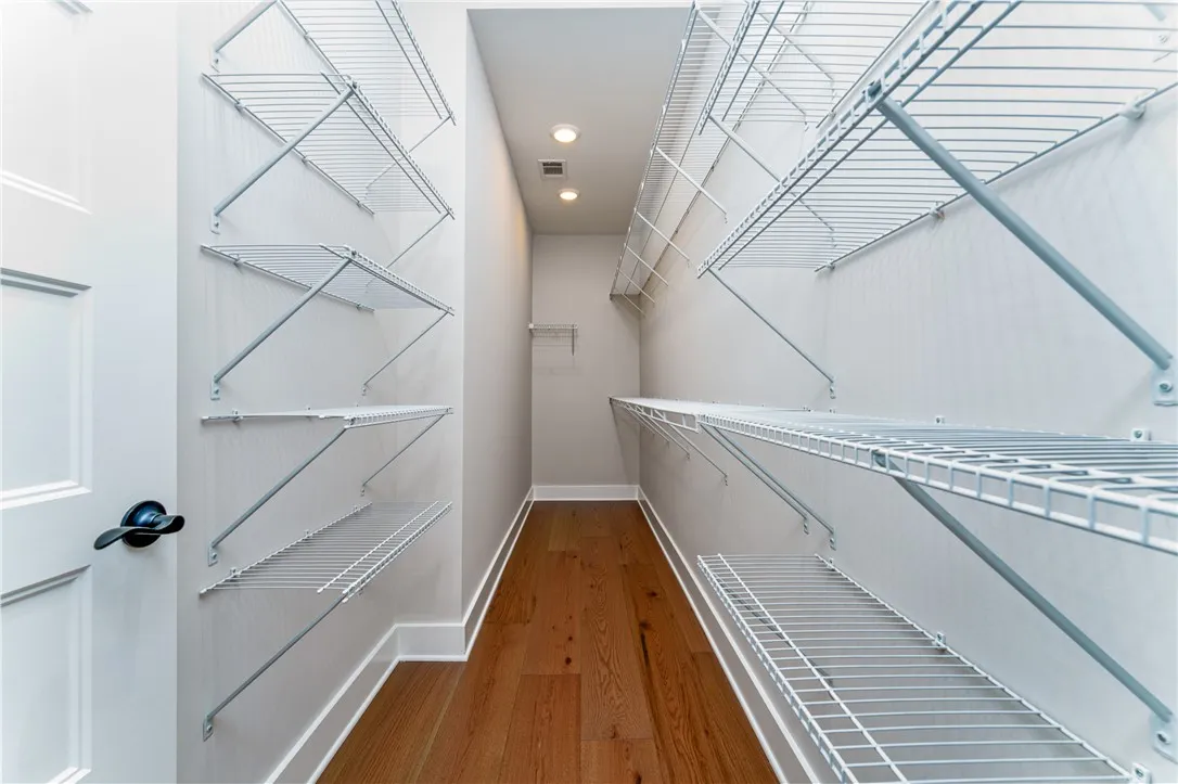 This spacious closet offers ample storage with durable wire shelving and warm hardwood flooring.