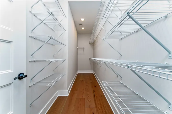 This spacious walk-in closet features ample storage and rich hardwood flooring.