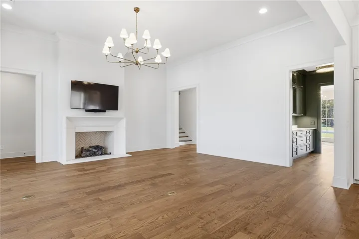 A refined living space showcases rich hardwood flooring, a statement chandelier, and an elegant fireplace.