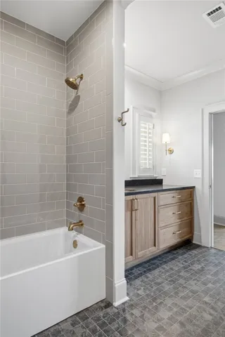 A well-appointed bathroom with a tile-surrounded tub and a vanity featuring ample storage.
