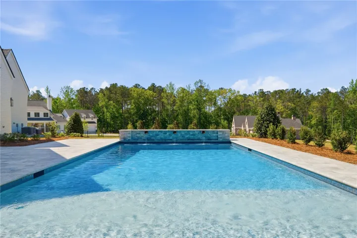 An inviting in-ground pool with a tranquil water feature anchors this property's serene outdoor space.