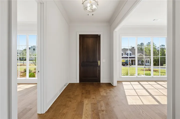 A welcoming entryway with lustrous hardwood flooring and an elegant dark wood door.