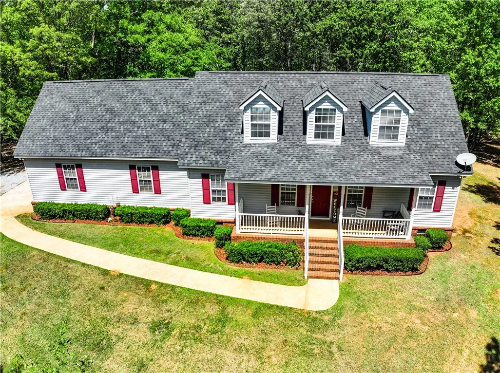 This charming home offers classic appeal with a welcoming front porch, nestled among lush greenery.