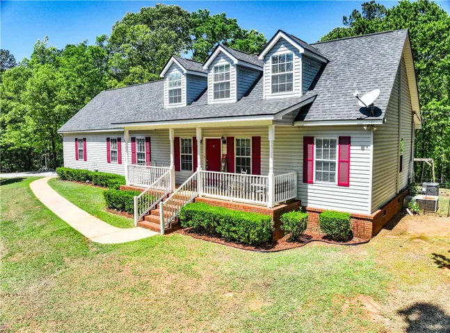 This charming home offers a welcoming facade with traditional architectural details and a lush green setting.