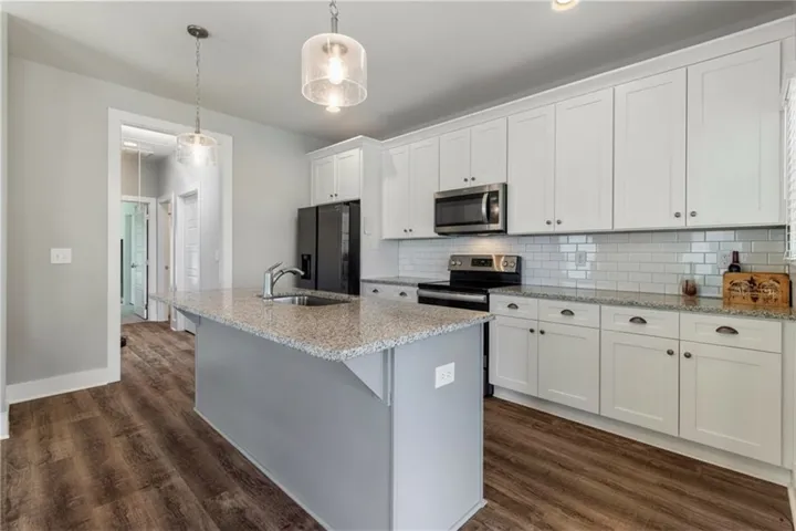 Polished granite countertops complement classic shaker cabinetry and rich wood floors in this modern kitchen.