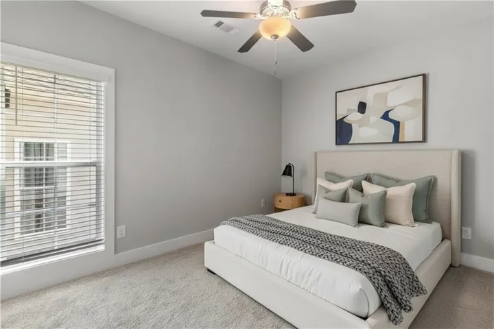 A tall window illuminates plush carpeted flooring in this comfortable sleeping space. Virtually staged.