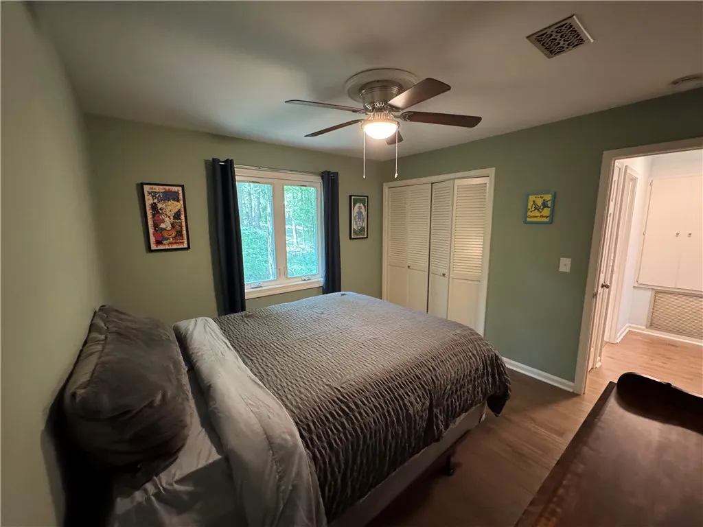 Hardwood floors and a window view of mature trees create a serene and private sleeping space.