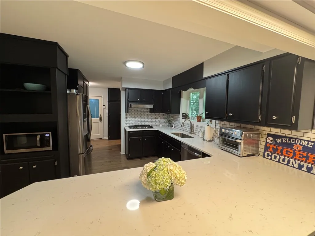 Culinary delights await in this modern kitchen, featuring sleek black cabinetry and pristine white countertops.