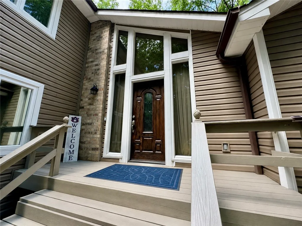 A welcoming entry features a paneled front door framed by tall windows and leading to a spacious porch.