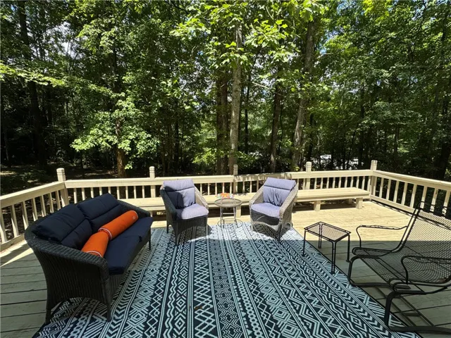 An inviting deck extends into a lush, private wooded backyard, perfect for peaceful outdoor living.