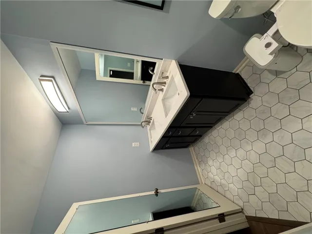 A well-lit bathroom features a double vanity with ample counter space and stylish hexagonal floor tiles.