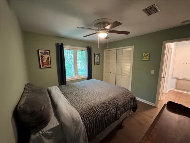 Hardwood floors and a window view of mature trees create a serene and private sleeping space.