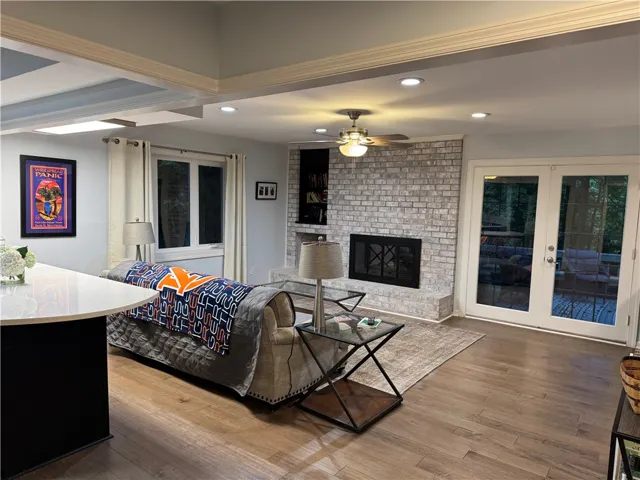 A welcoming living area boasts rich hardwood floors, a prominent brick fireplace, and access to the outdoors.