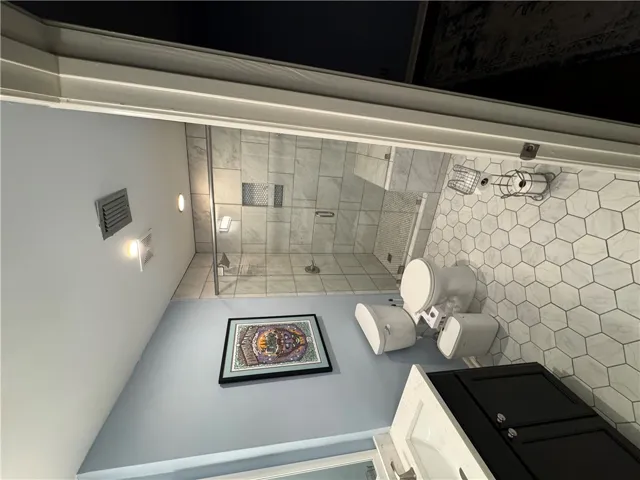 A well-appointed bathroom features a spacious glass-enclosed shower and hexagon-tiled flooring.