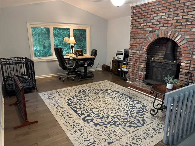 A spacious home office offers a cozy brick fireplace and ample natural illumination.