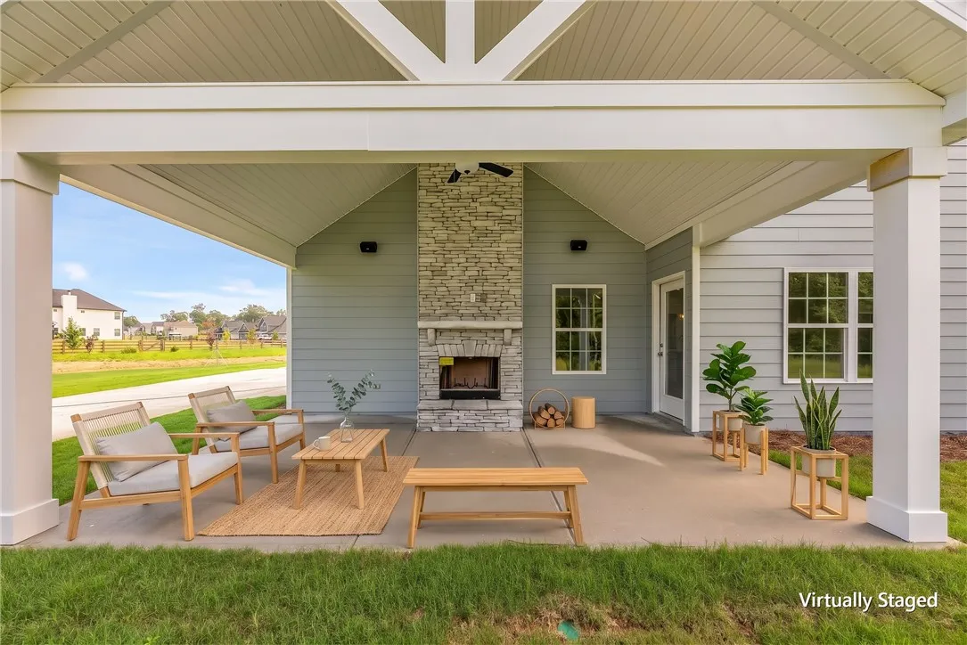 A vaulted covered patio features a monumental stone fireplace perfect for outdoor gatherings.