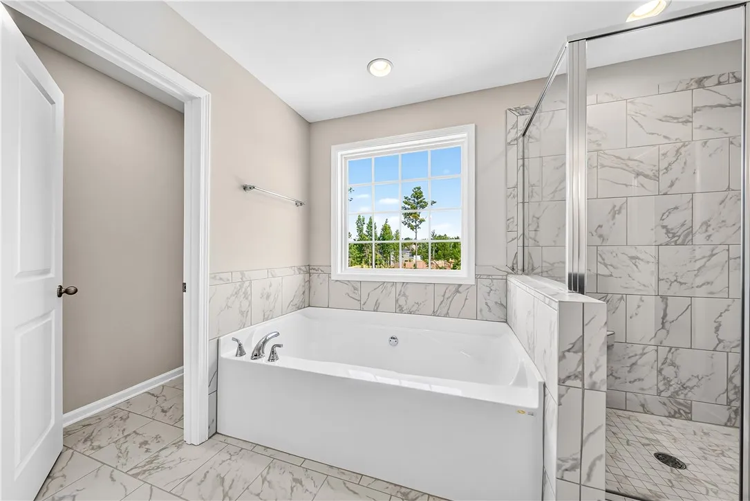 Fine tilework surrounds a deep soaking tub and a separate glass-enclosed shower.