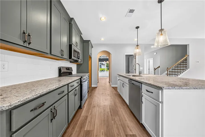 Rich wood floors anchor this kitchen workspace completed by stone counters and an expansive island.