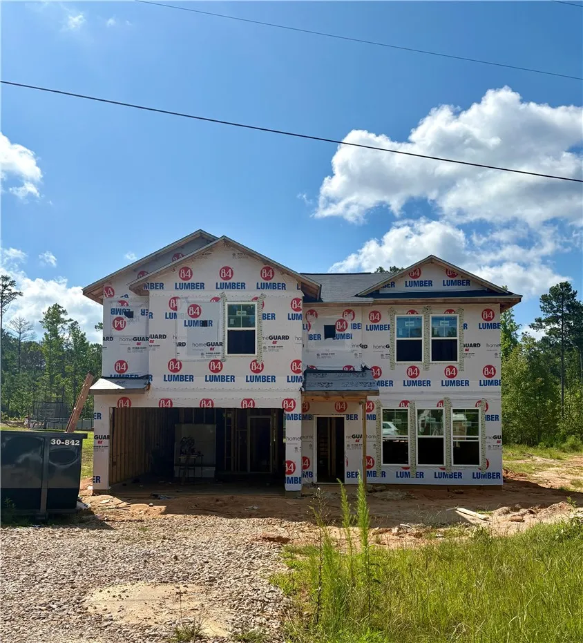 A newly framed residence, wrapped and awaiting its exterior finish, is nestled amongst natural surroundings.